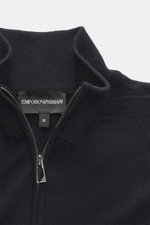 Nahaufnahme der Emporio Armani Strickjacke navy von oben, reine Schurwolle, weicher Griff, feines Strickbild, Slim Fit, verdeckter Zwei-Wege-Reißverschluss, gerippter Stehkragen, tonales Logo-Stitching, komfortable Rippbündchen.