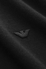 Nahaufnahme der schwarzen Emporio Armani Strickjacke schwarz aus reine Schurwolle mit weichem Griff, feinem Strickbild, tonalem Logo-Stitching, fotografiert aus seitlicher Perspektive.