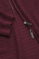 Close-up top view of the Emporio Armani Cardigan burgundy showing pure virgin wool fabric with a subtle textured knit pattern, ribbed cuffs, and a two-way zipper with logo stitching on the hem, featuring a ribbed stand-up collar and regular fit.