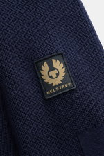Close-up front view of Belstaff Cardigan 'Commander' navy, showing pure cotton fabric with slightly textured quality, fine rib stitch pattern, flat knit details, and BELSTAFF woven label on the upper arm.