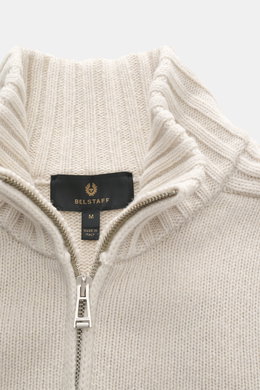 Close-up front view of the Belstaff Cardigan 'Watch' cream, showing pure wool coarse knit pattern, soft touch, rib knit elements, ribbed cuffs, slim fit, stand-up collar, two-way zipper, and BELSTAFF woven label on the chest.