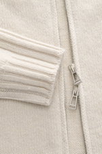 Close-up front view of Belstaff Cardigan 'Watch' cream showing pure wool fabric, soft touch, coarse knit pattern, rib knit cuffs, slim fit, stand-up collar, two-way zipper, BELSTAFF woven label on chest, and flexible ribbed cuffs.