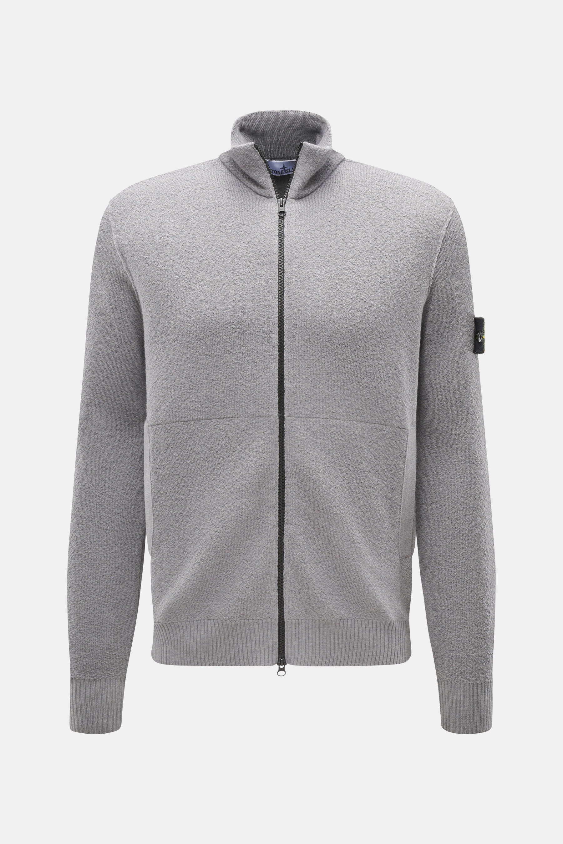 Stone Island Strickjacke grau, Frontansicht, aus reiner Schurwolle mit Zwei-Wege-Reißverschluss, hoch schließendem Kragen, Leistentaschen, Kompass-Badge am Arm, Rippbündchen, Regular Fit, weicher Griff, komfortables Essential für Herbst und Winter.