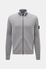 Stone Island Strickjacke grau, Frontansicht, aus reiner Schurwolle mit Zwei-Wege-Reißverschluss, hoch schließendem Kragen, Leistentaschen, Kompass-Badge am Arm, Rippbündchen, Regular Fit, weicher Griff, komfortables Essential für Herbst und Winter.