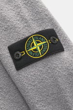 Stone Island Strickjacke grau aus reiner Schurwolle, Detailaufnahme des typischen Kompass-Badge auf Oberarm, weicher Griff, Rippbündchen.