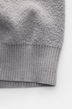 Nahaufnahme der Stone Island Strickjacke grau, Detail des weichen Strickmusters und Rippbündchens aus reiner Schurwolle.