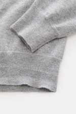 Nahaufnahme der Ärmelbündchen und Saum des Malo Cashmere Cardigan grau meliert, fotografiert von oben; reiner Cashmere, weicher Griff, feines Strickbild, Slim Fit, Fünf-Knopf-Leiste, V-Ausschnitt, komfortable Rippbündchen.
