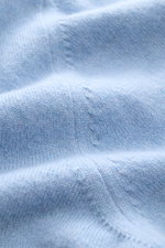 Nahaufnahme des hellblauen Malo Cashmere Cardigans mit feinem Strickbild und weichem Griff, fotografiert aus schräger Perspektive.