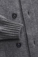 Close-up front view of Fioroni Cashmere cardigan dark grey melange showing fine knit pattern, black buttons, ribbed cuffs, and button placket.