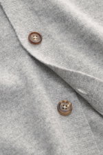Nahaufnahme des Fioroni Cashmere Cardigan grau meliert mit glatter Knopfleiste, feinem Strickbild, weichem Griff, Regular Fit und flexiblen Rippbündchen, gefertigt aus reinem Baby-Cashmere, fotografiert aus schräger Perspektive.
