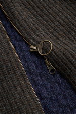 Nahaufnahme der Barbour Strickjacke 'Gamefair' multicolor mit grobem Melange-Strick und detailreichem Reißverschluss, fotografiert von oben.