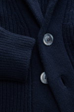 Nahaufnahme von Fedeli Cardigan 'Morgan' navy, fotografiert aus schräger Perspektive, zeigt Mix aus Schurwolle und Cashmere, sehr weicher Griff, voluminöses Strickbild mit Patent-Strickmuster, Regular Fit, Fünf-Knopf-Leiste, Schalkragen, aufgesetzte Hüftt