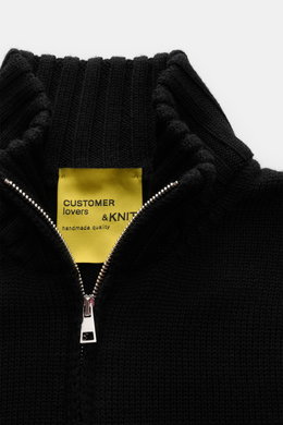 Nahaufnahme der B.F. Knitwear Merino Strickjacke schwarz, von oben fotografiert mit offenem Zwei-Wege-Reißverschluss, Stehkragen und mittlerem Strickbild.