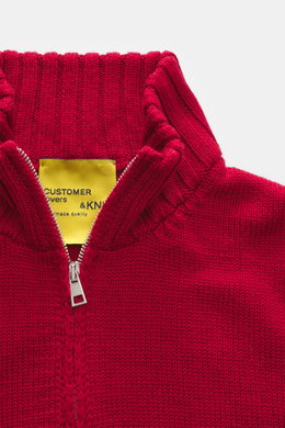 Nahaufnahme der B.F. Knitwear Merino Strickjacke rot mit Stehkragen und Zwei-Wege-Reißverschluss, seitlich fotografiert.