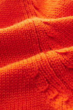 Nahaufnahme der orangefarbenen B.F. Knitwear Merino Strickjacke mit weichem Griff und mittelgroßem Strickbild aus reiner Merinowolle.