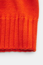 Nahaufnahme der B.F. Knitwear Merino Strickjacke orange im Slim Fit mit weichem Griff, mittlerem Strickbild und Rippbündchen, Detail von unten.
