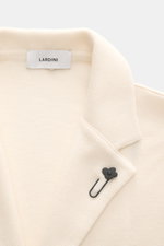 Close-up front angle of Lardini Knit blazer cream showing fine knit pattern, tailored lapel with flower pin, pure wool fabric.

Description: <p>With a classic silhouette and made from pure wool, the knit blazer by LARDINI brings style and personality to y
