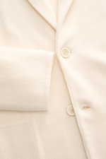 Nahaufnahme des Lardini Strickblazer creme aus reiner Wolle, slim fit mit zwei Knöpfen, feinem Strickbild, weichem Griff und aufgesetzter Hüfttasche, frontal fotografiert.
