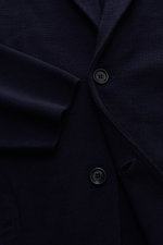 Close-up front view of Lardini Knit blazer navy showing fine knit pattern, two buttons, lapel with flower pin, and sleeve cuff.

Description: <p>With a classic silhouette and made from pure wool, the knit blazer by LARDINI brings style and personality to 