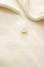 Lardini Cashmere Strickblazer creme in Nahaufnahme von oben, feines Strickbild, weicher Griff, Knopf und Kanten des taillierten Slim Fit Blazers sichtbar.