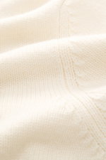 Nahaufnahme der Della Ciana Strickjacke creme aus mittelfeinem Strickbild, weichem Griff, Mix aus Cashmere und Merinowolle, Regular Fit, Stehkragen, Zwei-Wege-Reißverschluss und flexiblen Rippbündchen, fotografiert aus schräger Perspektive.