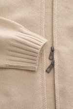 Della Ciana Strickjacke beige, Nahaufnahme von Ärmel und Reißverschluss im Regular Fit, Mix aus Cashmere und Merinowolle, weicher Griff, mittelfeines Strickbild, Stehkragen, Zwei-Wege-Reißverschluss, flexible Rippbündchen, frontale Perspektive.