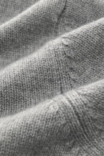 Nahaufnahme des mittelfeinen Strickbilds der Della Ciana Strickjacke grau meliert aus Cashmere und Merinowolle mit weichem Griff, aufgenommen aus schräger Perspektive, Regular Fit, Zwei-Wege-Reißverschluss, Stehkragen und flexible Rippbündchen.