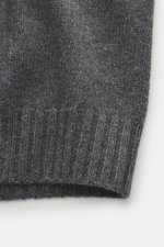 Nahaufnahme der Della Ciana Strickjacke dunkelgrau meliert, Detailaufnahme des mittelfeinen Strickbilds, weicher Griff, aus Mix aus Cashmere und Merinowolle, flexible Rippbündchen sichtbar, fotografiert aus seitlicher Draufsicht.