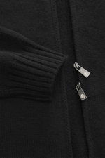 Nahaufnahme der Della Ciana Strickjacke schwarz, von schräg oben fotografiert, mit mittelfeinem Strickbild, Stehkragen, zwei-Wege-Reißverschluss, flexiblen Rippbündchen, Regular Fit, weichem Griff aus Cashmere und Merinowolle.