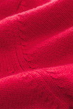 Nahaufnahme der roten Della Ciana Strickjacke, Detailansicht mittelfeines Strickbild, Mix aus Cashmere und Merinowolle, weicher Griff, Regular Fit, Stehkragen, Zwei-Wege-Reißverschluss, flexible Rippbündchen.