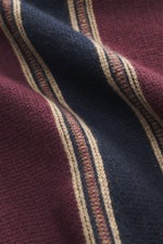 Nahaufnahme des Guest In Residence Cashmere Cardigan bordeaux/navy/sand gestreift aus reiner Cashmere, weicher Griff, mittelfeines Strickbild. Regular Fit, glatte Knopfleiste, V-Neck, seitliche Perspektive.