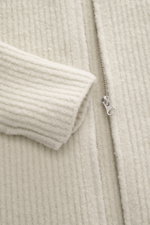 Nahaufnahme der Massimo Osti Studio Strickjacke creme von schräg oben, zeigt voluminöses Strickbild, robusten Reißverschluss, Umlegekragen, Slim Fit, weichen Griff, Mix aus Wolle und Microfaser.
