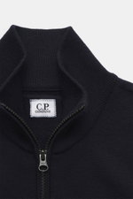 Nahaufnahme der C.P. Company Strickjacke navy von vorne, Strick aus Schurwolle und Microfaser, feines Strickbild, Regular Fit, Zwei-Wege-Reißverschluss, Stehkragen, Oberarmtasche, Linsen-Detail.