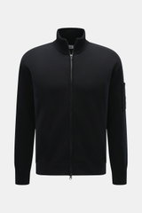 C.P. Company Strickjacke schwarz, Frontansicht, Regular Fit, Strick aus Schurwolle und Microfaser, feines Strickbild, Zwei-Wege-Reißverschluss, Stehkragen, Tasche am Oberarm, Linsen-Detail.