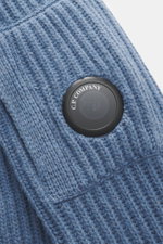 Nahaufnahme der labeltypischen Linse der C.P. Company Strickjacke graublau, Strick aus Schurwolle/Microfaser, weich, voluminös, Slim Fit.