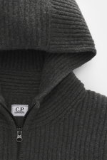Nahaufnahme der Kapuze und des Reißverschlusses der C.P. Company Strickjacke dunkelgrau, Strick aus Schurwolle und Microfaser, voluminöses Strickbild.