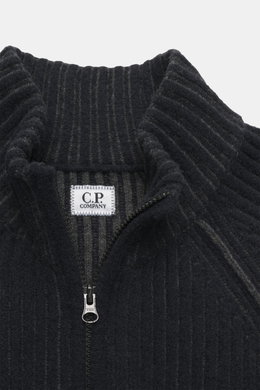Nahaufnahme von C.P. Company Strickjacke navy/dunkelgrau, fotografiert von oben, mit Stehkragen, voluminösem Strickbild, robustem Zwei-Wege-Reißverschluss, Zipper-Tasche am Oberarm, Raglanärmeln, Regular Fit, labeltypischem Linsen-Detail, weicher Qualität