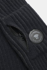 Nahaufnahme der C.P. Company Strickjacke navy/dunkelgrau mit voluminösem Strickbild, Zipper-Tasche am Oberarm und labeltypischem Linsen-Detail.