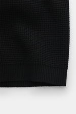 Nahaufnahme der C.P. Company Strickjacke 'Metropolis' schwarz, perspektivisch von unten, mit Waffelmuster, weichem Griff, Regular Fit, Kapuze, Reißverschluss, Arm-Tasche mit Logo und Rippbündchen.