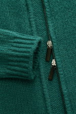 Nahaufnahme der Iris von Arnim Cashmere-Seide Strickjacke 'Felias' grün, Slim Fit mit voluminösem Strickbild, zwei Wege Reißverschluss, Hornanhänger, Rippstrickkragen und Rippbündchen, sehr weicher Griff, Mix aus Cashmere und Seide, fotografiert frontal.