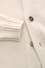 Filippo de Laurentiis Cardigan creme, Nahaufnahme von Knöpfen, Umlegekragen, weicher, voluminöser Griff, mittelfeines Strickbild, Rippbündchen, Mix aus Cashmere, Seide, Microfaser, Oversized Fit, Detailfoto von vorne.