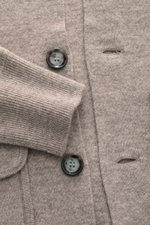 Nahaufnahme des Allude Cardigans beige meliert, fotografiert aus frontaler Perspektive, zeigt feines Strickbild, weiche Rippbündchen und glatte Knopfleiste aus Schurwoll-Cashmere-Mix.
