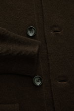 Nahaufnahme des Allude Cardigan dunkelbraun von vorne zeigt weichen Schurwoll-Cashmere-Mix, glatte Knopfleiste, Stehkragen, Fronttaschen und Rippbündchen.