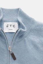 Nahaufnahme der FTC Cashmere Strickjacke hellblau meliert von oben, zeigt gerippten Stehkragen, feines Strickbild und Leder-Zipper.