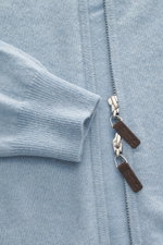 Nahaufnahme der FTC Cashmere Strickjacke hellblau meliert von oben, zeigt feines Strickbild, verdeckten Zwei-Wege-Reißverschluss mit Leder-Logo und gerippten Stehkragen aus reiner Fair-Trade-Cashmere mit weichem Griff.