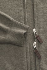 Nahaufnahme der FTC Cashmere Strickjacke graugrün von vorne, zeigt feines Strickbild, verdeckten Zwei-Wege-Reißverschluss mit Leder-Logo und gerippten Stehkragen. Fair-Trade-Cashmere, OEKO-TEX® Standard 100, weicher Griff, Regular Fit, flexible Rippbündch