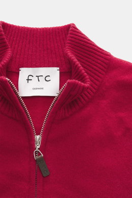 Nahaufnahme der FTC Cashmere Strickjacke rot von oben, zeigt gerippten Stehkragen, verdeckten Zwei-Wege-Reißverschluss mit Leder-Logo-Zipper, feines Strickbild aus Fair-Trade-Cashmere, OEKO-TEX® zertifiziert, Regular Fit und weichen Griff.