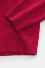 Nahaufnahme der Ärmel und Saum der FTC Cashmere Strickjacke rot, fair-trade, weich, feines Strickbild, gerippter Bund aus nachhaltigem Cashmere.