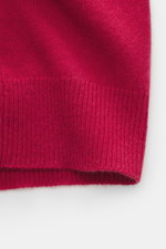 Nahaufnahme der roten FTC Cashmere Strickjacke rot von unten, zeigt das feine Strickbild mit geripptem Saum, Fair-Trade-Cashmere, weich und nachhaltig.