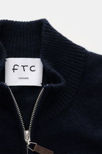 Close-up front view of FTC Cashmere cardigan navy showing ribbed standing collar, concealed two-way zip with leather logo detail, and fine knit texture.

Description: <p>Fair Trade cashmere, timeless design: This cardigan by FTC has been sustainably produ